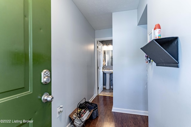 hall featuring dark wood-type flooring, a textured ceiling, and sink