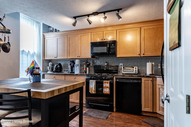 kitchen with rail lighting, a kitchen breakfast bar, dark hardwood / wood-style flooring, a textured ceiling, and black appliances