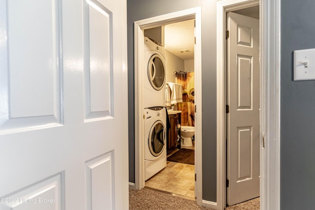 clothes washing area featuring light colored carpet and stacked washing maching and dryer