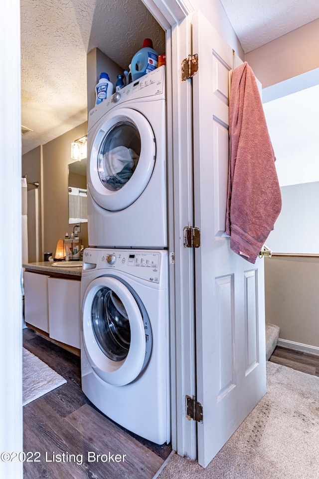 washroom featuring stacked washer / dryer, a textured ceiling, and hardwood / wood-style floors