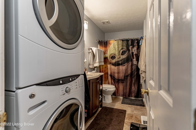 laundry room with a textured ceiling and stacked washer and dryer