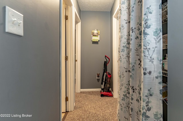 corridor with light colored carpet and a textured ceiling