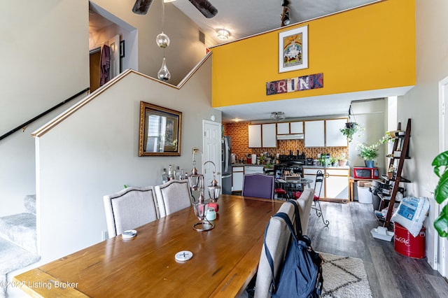 dining space with ceiling fan, track lighting, wood-type flooring, and high vaulted ceiling