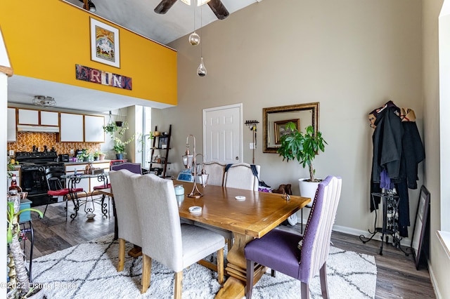 dining room featuring a high ceiling, ceiling fan, and hardwood / wood-style flooring