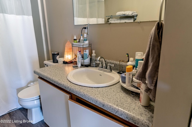 bathroom with hardwood / wood-style flooring, toilet, and vanity