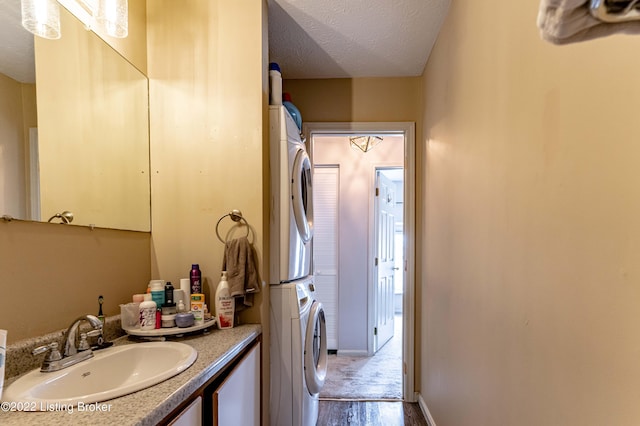 bathroom with a textured ceiling, stacked washer / drying machine, hardwood / wood-style flooring, and vanity