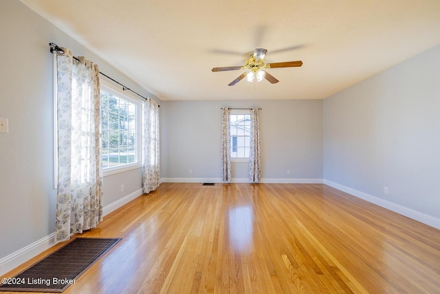 unfurnished room featuring a wealth of natural light, ceiling fan, and light wood-type flooring