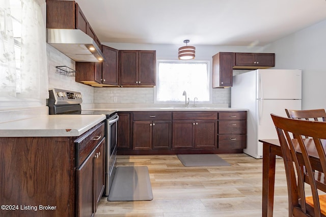 kitchen featuring stainless steel range with electric cooktop, exhaust hood, white refrigerator, sink, and light wood-type flooring