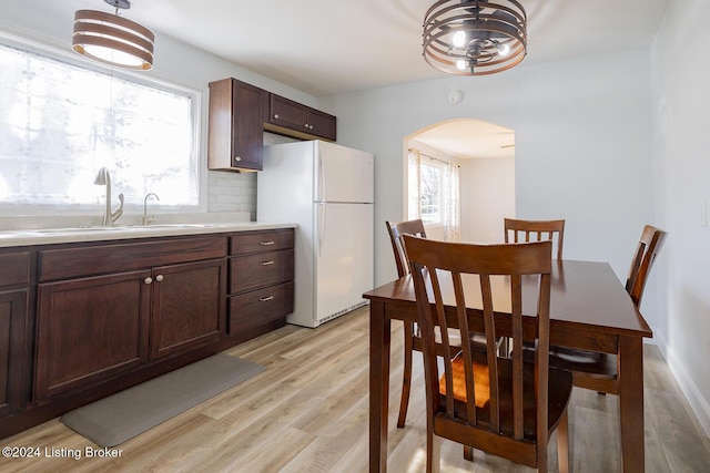 kitchen featuring sink, backsplash, white fridge, pendant lighting, and dark brown cabinets