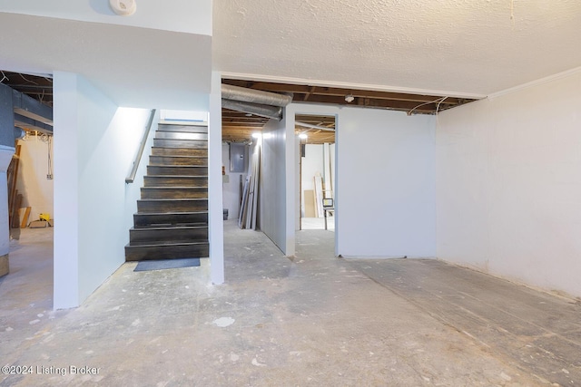 basement featuring electric panel and a textured ceiling