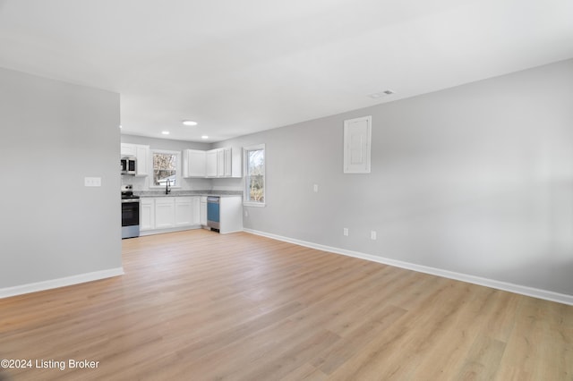 unfurnished living room featuring sink and light hardwood / wood-style floors