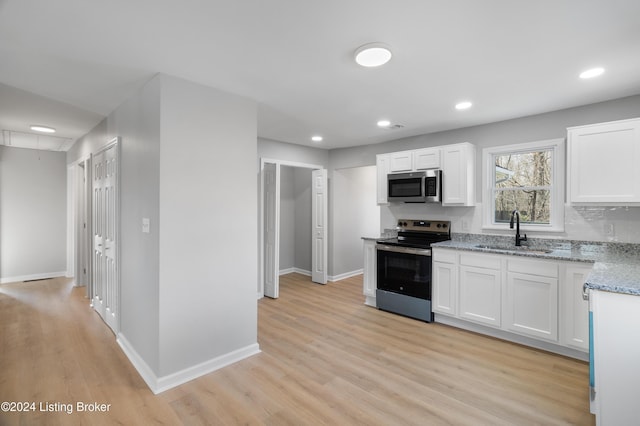 kitchen featuring white cabinets, sink, appliances with stainless steel finishes, light hardwood / wood-style floors, and light stone counters