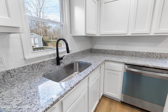 kitchen with white cabinetry, dishwasher, light stone countertops, and sink