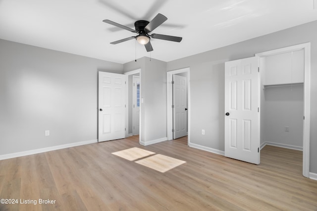 unfurnished bedroom featuring ceiling fan, light hardwood / wood-style floors, a walk in closet, and a closet