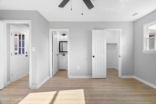 unfurnished bedroom featuring ceiling fan, light wood-type flooring, a spacious closet, and a closet