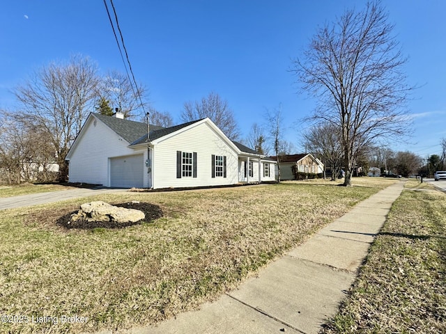 view of side of property with an attached garage, a lawn, driveway, and a chimney