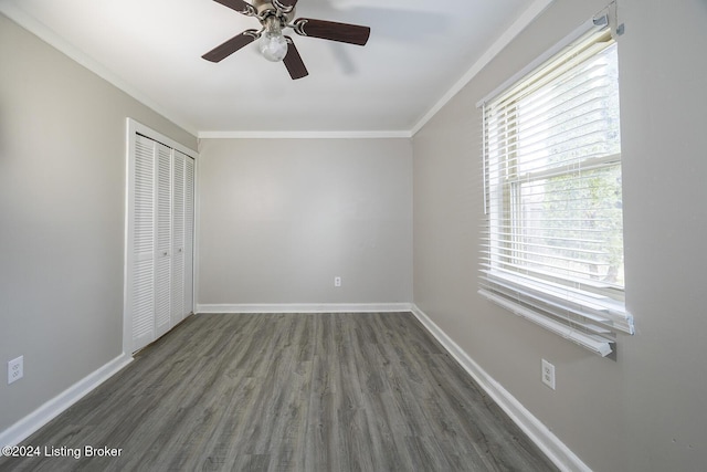 unfurnished bedroom with ceiling fan, crown molding, dark wood-type flooring, and a closet