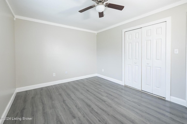 unfurnished bedroom with ceiling fan, dark hardwood / wood-style flooring, ornamental molding, and a closet