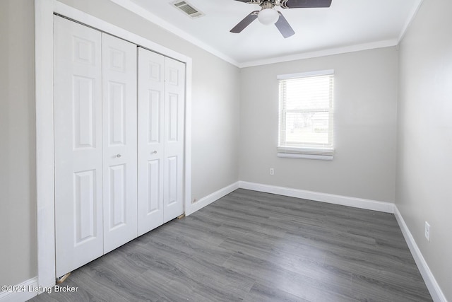 unfurnished bedroom with hardwood / wood-style flooring, ceiling fan, crown molding, and a closet