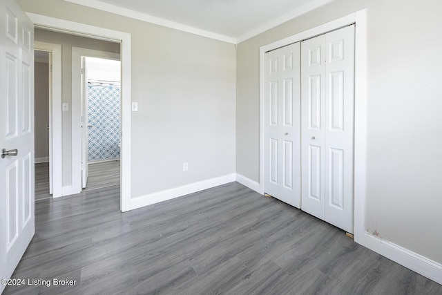 unfurnished bedroom featuring a closet, dark hardwood / wood-style floors, and ornamental molding