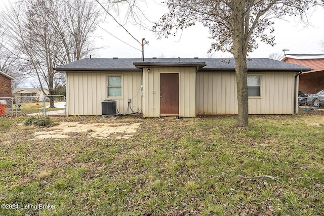 rear view of house with cooling unit and a yard