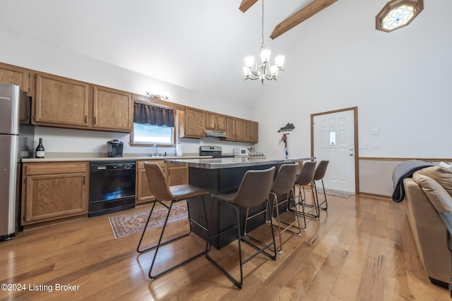 kitchen featuring a kitchen breakfast bar, light wood-type flooring, black dishwasher, and hanging light fixtures