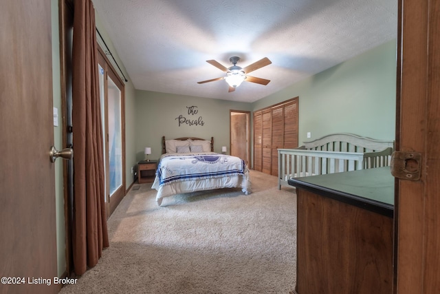 carpeted bedroom with ceiling fan, a textured ceiling, and a closet