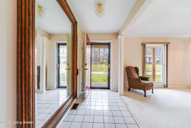 foyer entrance featuring ornate columns, light tile patterned floors, and a healthy amount of sunlight