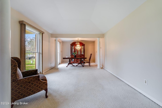 living area featuring carpet, decorative columns, and vaulted ceiling