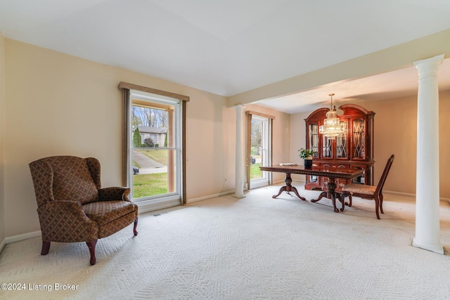 living area featuring carpet, ornate columns, and an inviting chandelier