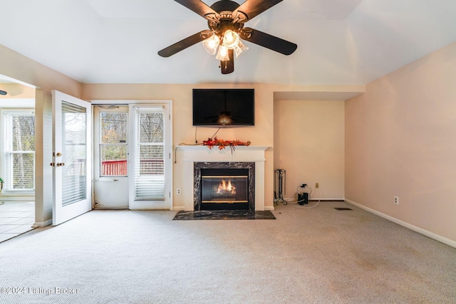 unfurnished living room with ceiling fan, a fireplace, and light colored carpet