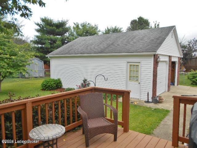 wooden terrace with a garage, an outbuilding, and a yard