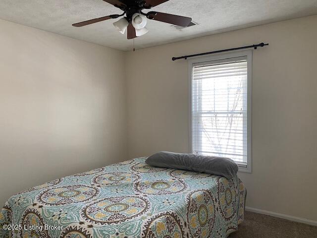 bedroom featuring ceiling fan, carpet flooring, and a textured ceiling