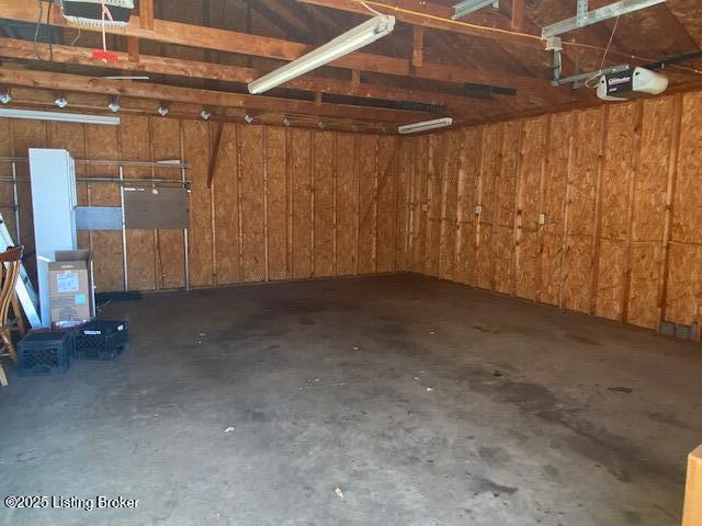 garage featuring a garage door opener and wooden walls