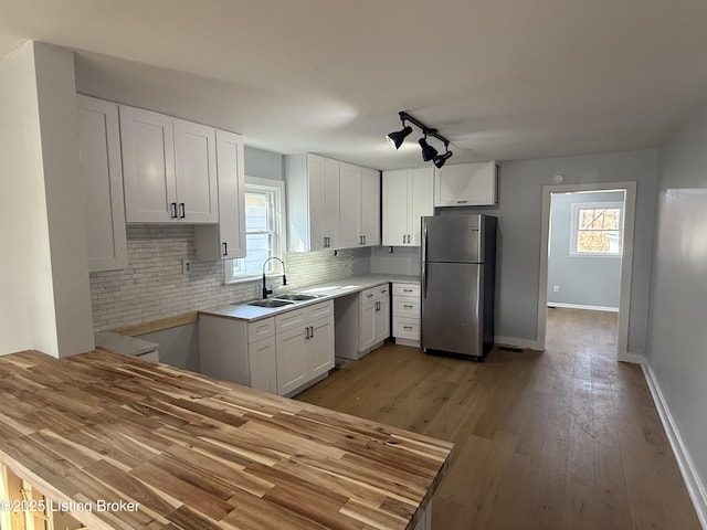 kitchen with sink, stainless steel appliances, white cabinets, decorative backsplash, and light wood-type flooring