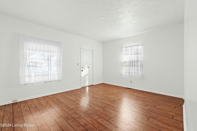 empty room featuring hardwood / wood-style flooring, a textured ceiling, and a wealth of natural light