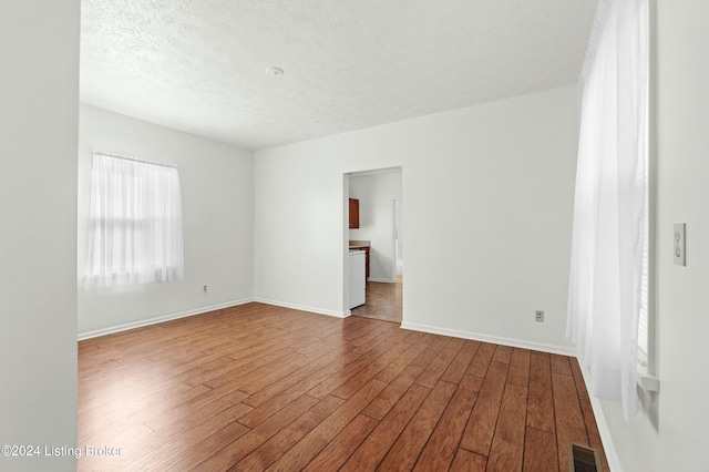 empty room featuring wood-type flooring and a textured ceiling