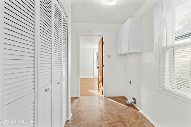 hallway with light tile patterned flooring, a textured ceiling, and a wealth of natural light