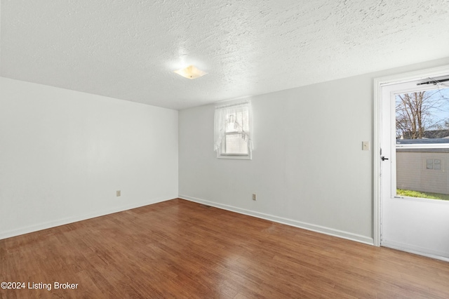 spare room featuring a textured ceiling, hardwood / wood-style flooring, and a wealth of natural light