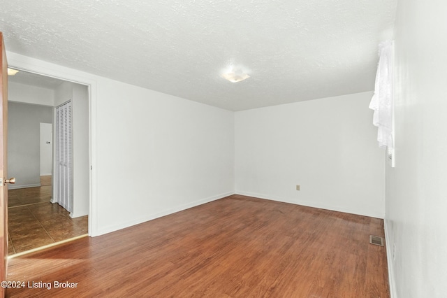 empty room with a textured ceiling and hardwood / wood-style flooring