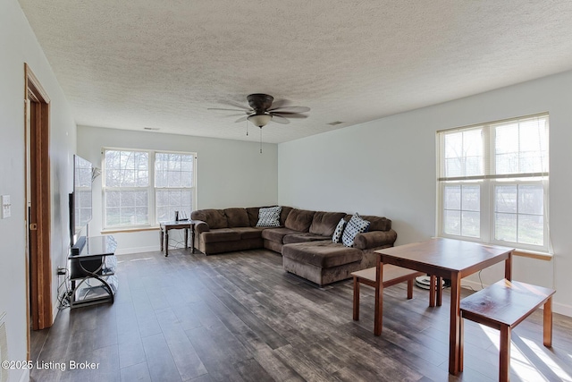 living room featuring a textured ceiling, dark wood-type flooring, ceiling fan, and a healthy amount of sunlight