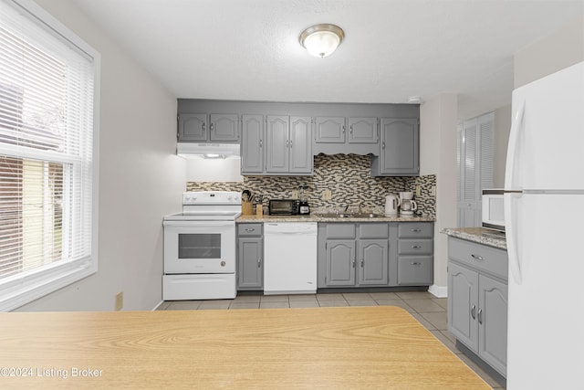 kitchen with white appliances, sink, gray cabinets, light tile patterned floors, and tasteful backsplash