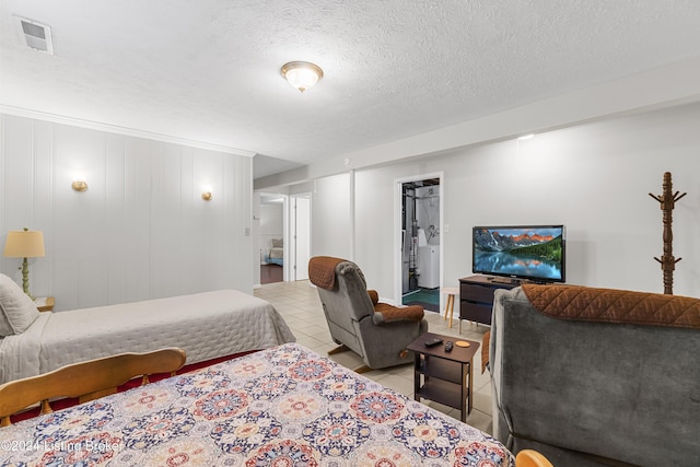 bedroom featuring a textured ceiling, connected bathroom, and light tile patterned floors