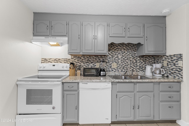 kitchen featuring gray cabinets, white appliances, sink, and tasteful backsplash