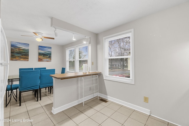 kitchen featuring a textured ceiling, ceiling fan, light tile patterned floors, and rail lighting