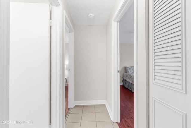 hall with a textured ceiling and light wood-type flooring