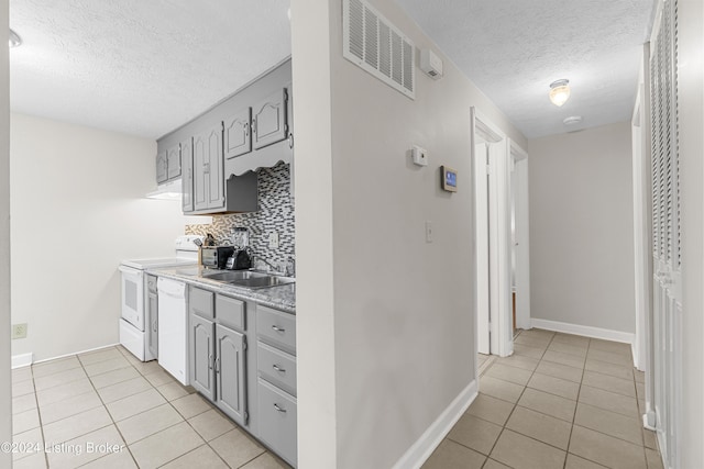 kitchen with white appliances, gray cabinets, a textured ceiling, tasteful backsplash, and light tile patterned flooring