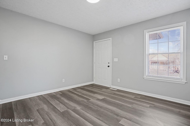 spare room featuring a textured ceiling and dark hardwood / wood-style floors