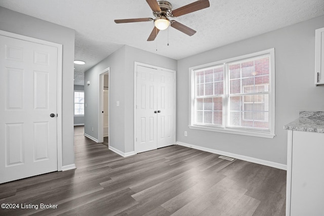 unfurnished bedroom featuring ceiling fan, dark hardwood / wood-style flooring, and a textured ceiling