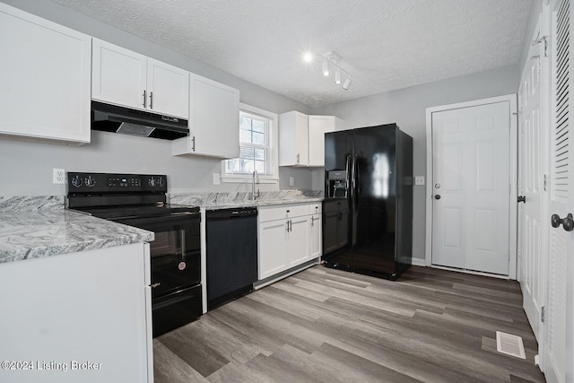 kitchen featuring light stone counters, track lighting, a textured ceiling, white cabinets, and black appliances